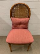 A cane back hall chair with pink upholstery seat and cushion