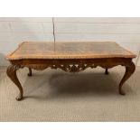 A carved yew style coffee table with glass top (H44cm W107cm D47cm)