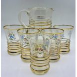 A vintage glass water jug and five glasses with gilt ribbing to centre and decorative flowers motif