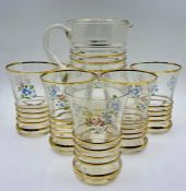 A vintage glass water jug and five glasses with gilt ribbing to centre and decorative flowers motif