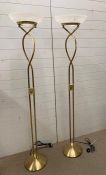 A pair of contemporary brass effect floor standing lamps with glass shades