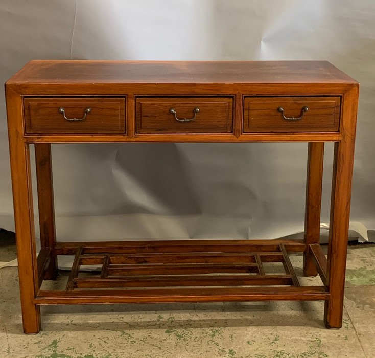 An oriental style hard wood console table with three drawers to centre and shelf (H80cm W100cm