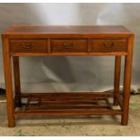 An oriental style hard wood console table with three drawers to centre and shelf (H80cm W100cm