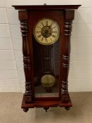 A mahogany wall clock with turned pillars to case and glazed door opening to reveal clock face (