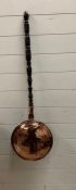 A copper bed pan with mahogany handle