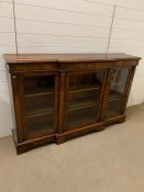 A Victorian breakfront walnut side cabinet with floral inlay and glazed doors enclosing shelves (