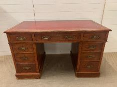 An oak three drawer pedestal desk with red leather top. (H72cm W122cm D65cm)