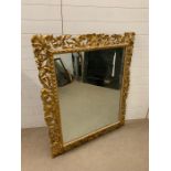 A gilt wood wall mirror with a profusely carved frame AF (130cm x 107cm)