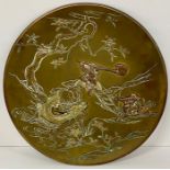 An oriental brass and copper plate, on feet depicting warriors fighting among the lotus flowers