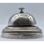 A white metal desk bell, indistinct mark to base.