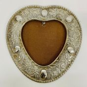 An antique white metal heart shaped picture frame