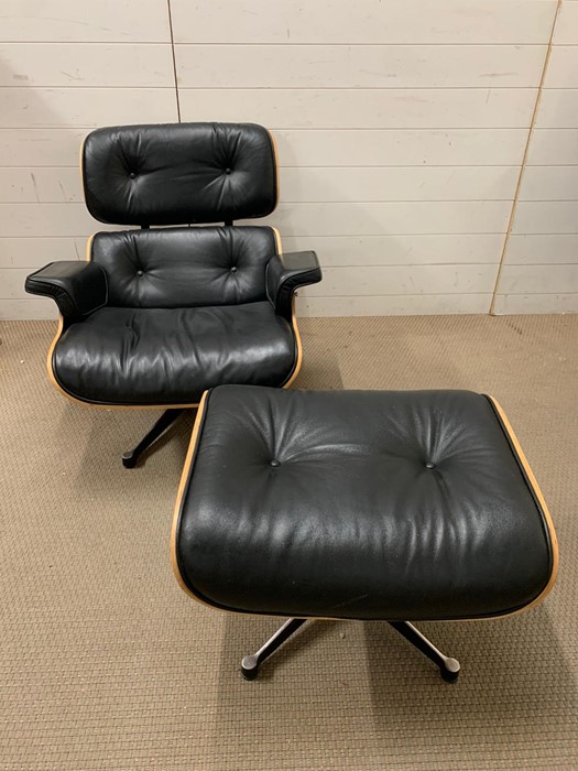 A rosewood lounge chair and ottoman. After Charles and Roy Eames for Herman Milner with black