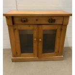 A pine side cupboard with glazed double doors (H82cm W89cm D37cm)