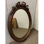 An oval gilt wall mirror with ribbon details to top and bottom (94cm x132cm)
