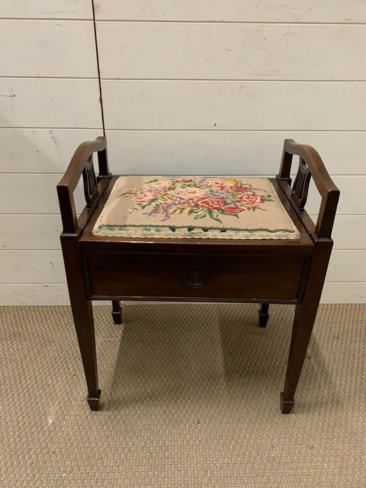 A mahogany piano stool with tapestry seat