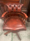 A leather captains chair on wheels spindled and button back