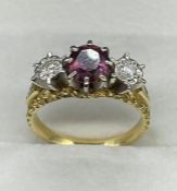 A three stone ring with central ruby and diamonds to either side on an 18ct gold mount.