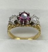 A three stone ring with central ruby and diamonds to either side on an 18ct gold mount.