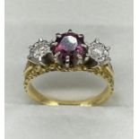 A three stone ring with central ruby and diamonds to either side on an 18ct gold mount.