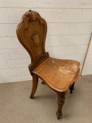 A carved wooden hall chair with shield back on turned legs