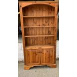 An open bookcase with cupboard under on bracket feet (H187cm W99cm D31cm)