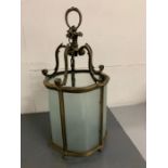 A Victorian brass hanging lantern with leaf, copped stem curved glass panels and turned brass feet