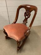 A mahogany rocking chair with pink upholstery