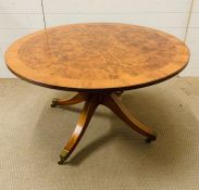 A Walnut center table, with burr walnut string inlay on sabre legs.