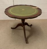 A tilt top side table with green leather top and scalloped edges