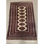 A cream and red carpet/rug with diamond pattern to centre (196cm x 128cm)