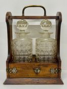 An oak Tantalus with two cut glass decanters (H35cm W25cm D14cm)