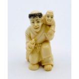 A signed ivory netsuke of a man carrying a child.