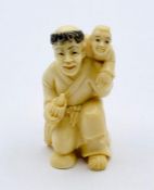 A signed ivory netsuke of a man carrying a child.