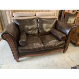 A two seater leather sofa on a mahogany frame with bolster cushions to each end
