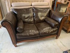 A two seater leather sofa on a mahogany frame with bolster cushions to each end