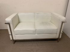 A two seater white faux leather sofa with chrome frame (marks to leather) (H68cm W130cm D70cm)