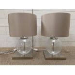 A pair of contemporary table lamps with glass centre on chrome base