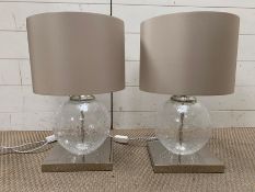 A pair of contemporary table lamps with glass centre on chrome base