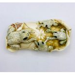 An ivory figure of four frogs on a lily pad.