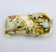 An ivory figure of four frogs on a lily pad.