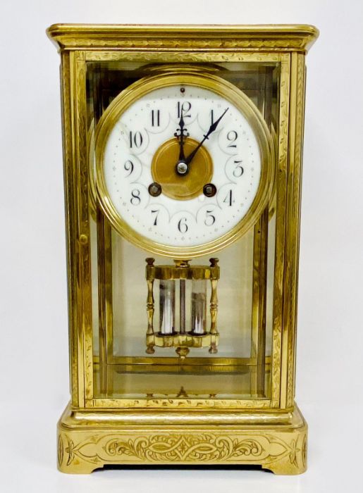 An eight day enamel faced eight day clock in a decorative engraved brass case.