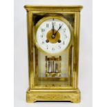 An eight day enamel faced eight day clock in a decorative engraved brass case.