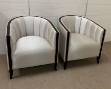A pair of tub chairs with black rim coming down to legs
