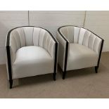 A pair of tub chairs with black rim coming down to legs