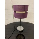 A chrome bedside lamp with purple shade
