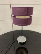 A chrome bedside lamp with purple shade