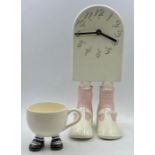 Two novelty items a clock on legs and a cup on legs