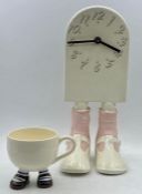 Two novelty items a clock on legs and a cup on legs