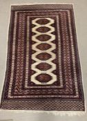 A cream and red carpet/rug with diamond pattern to centre (196cm x 128cm)