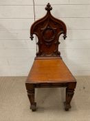 A regency style mahogany hall chair carved back above a solid seat